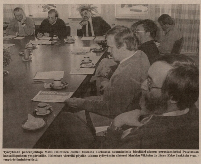 Pöydän ääressä istuu miehiä papereita edessään kokouksessa
