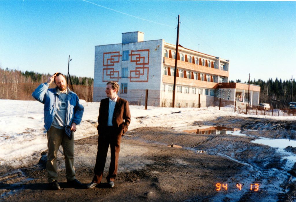 Kaksi miestä seisoo kerrostalorakennuksen edessä